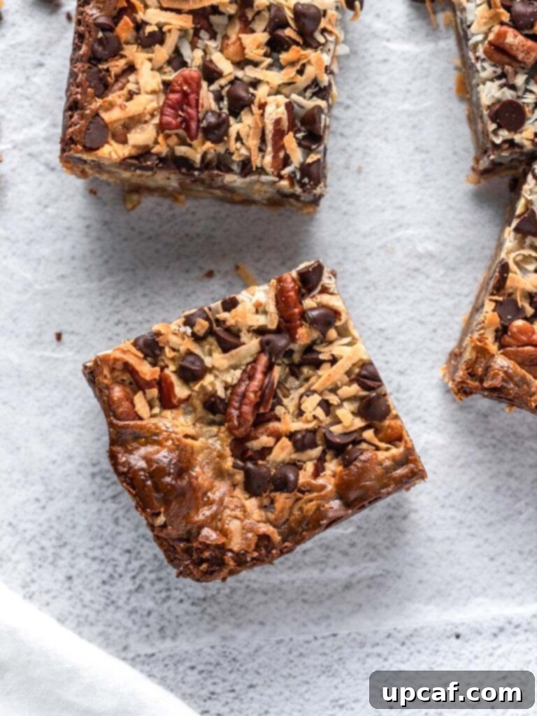 Golden Coconut Dream Bars 2 Top-down close-up view of golden-brown coconut magic bars, showcasing the gooey layers of coconut, chocolate, and nuts on a graham cracker crust.