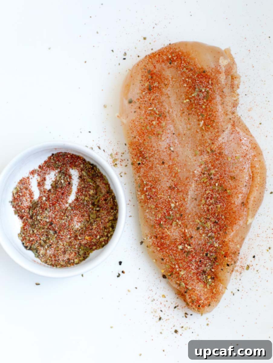 Creamy Spinach Artichoke Stuffed Chicken 4 Top down shot of raw chicken breast with seasoning on it.