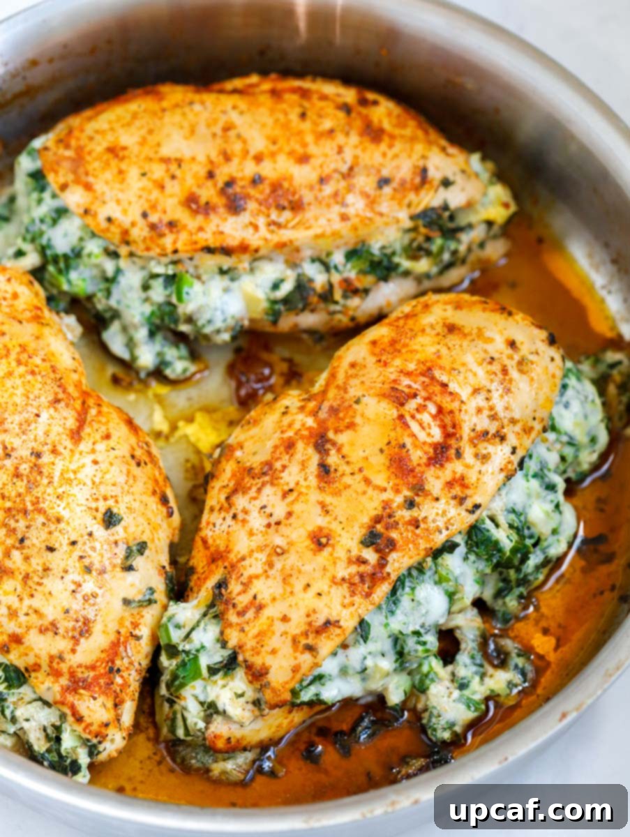 Creamy Spinach Artichoke Stuffed Chicken 8 Side shot of three spinach stuffed chicken breasts in a pan.