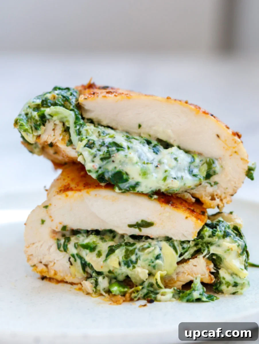 Creamy Spinach Artichoke Stuffed Chicken 9 Cheesy spinach stuffed chicken breast cut in half and stacked on top of each other.