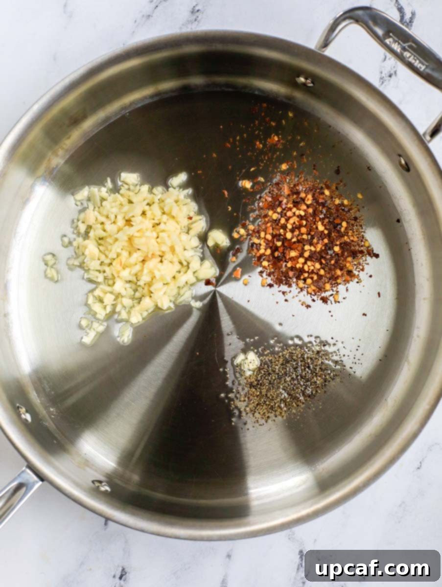 Raging Inferno Pasta 4 Top down shot of garlic, pepper and chili flakes sizzling in olive oil.