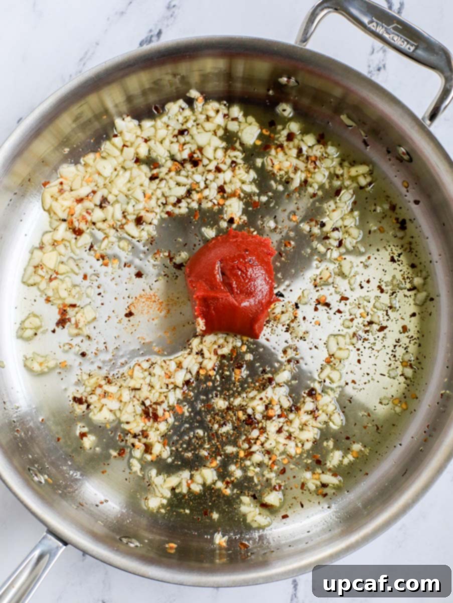 Raging Inferno Pasta 5 Top down shot of tomato paste added to the pan with aromatics.