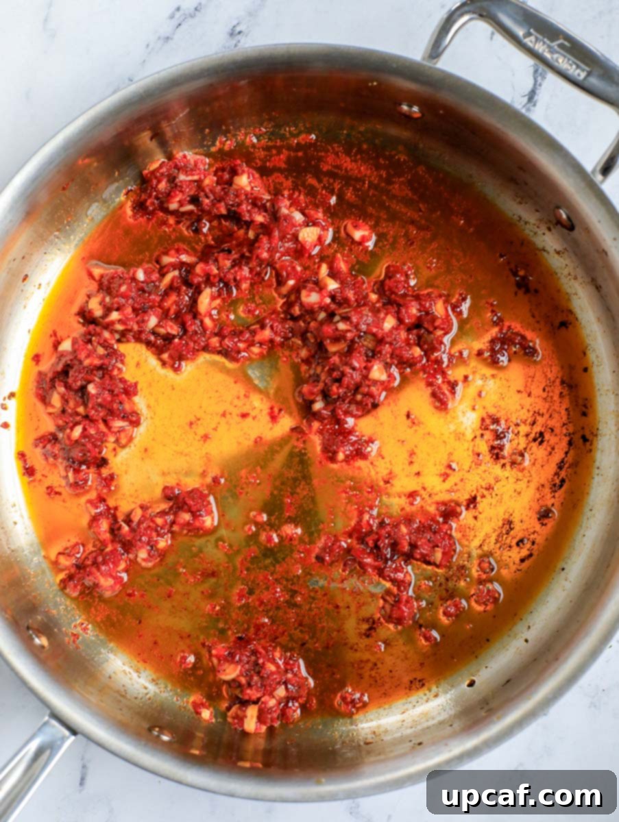 Raging Inferno Pasta 6 Top down shot of mixing tomato paste with aromatics in a skillet.