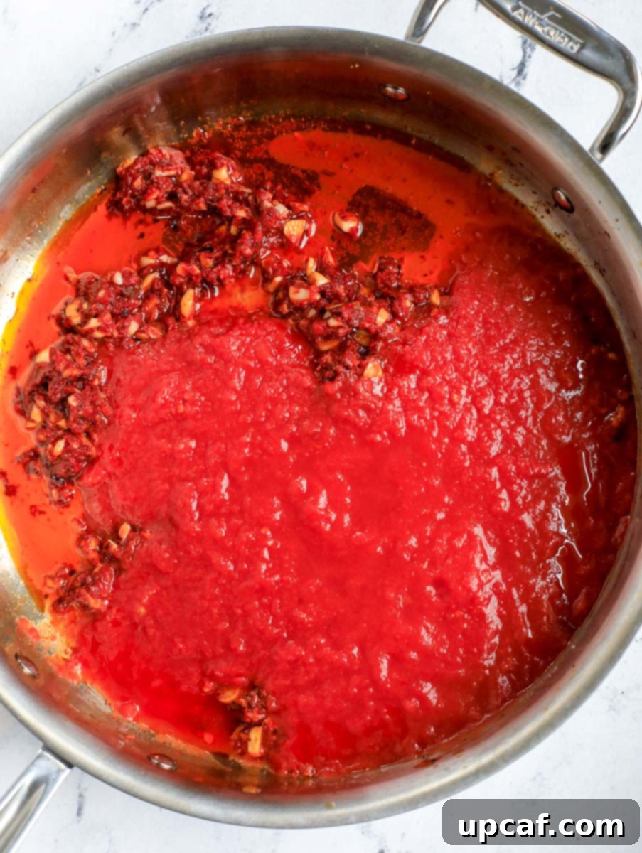 Raging Inferno Pasta 8 Adding crushed tomato sauce to the pot with cooked aromatics and tomato paste.