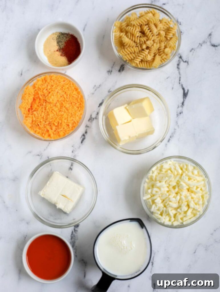 Fiery Buffalo Chicken Pasta Bake 3 Ingredients laid out for Buffalo Chicken Mac and Cheese including pasta, milk, chicken, butter, flour, various cheeses, and spices.