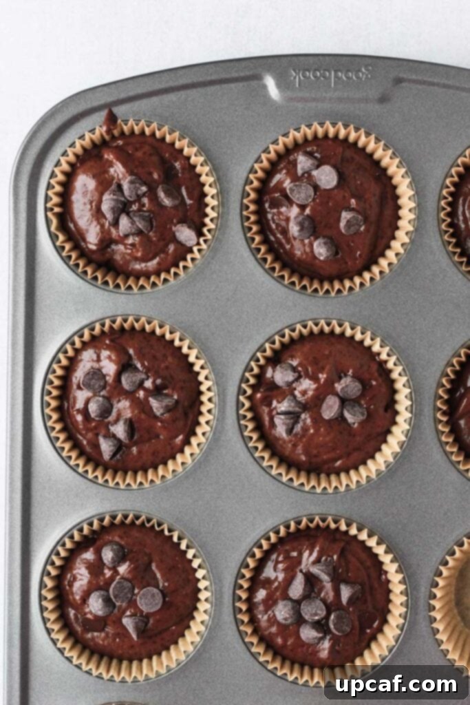 Double chocolate chip muffins batter filled into a muffin pan, ready for baking.