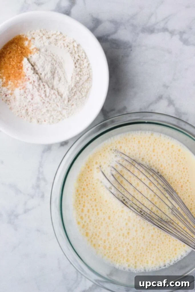 Top down shot of wet ingredients and dry ingredients in separate glass bowls, ready for mixing.