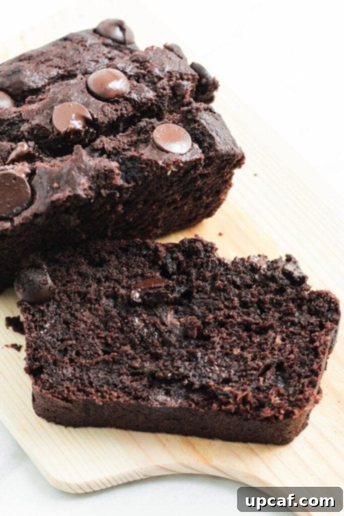A perfectly baked, thick slice of chocolate banana bread, showing its delightful texture and chocolate chips, resting on a small wooden cutting board.
