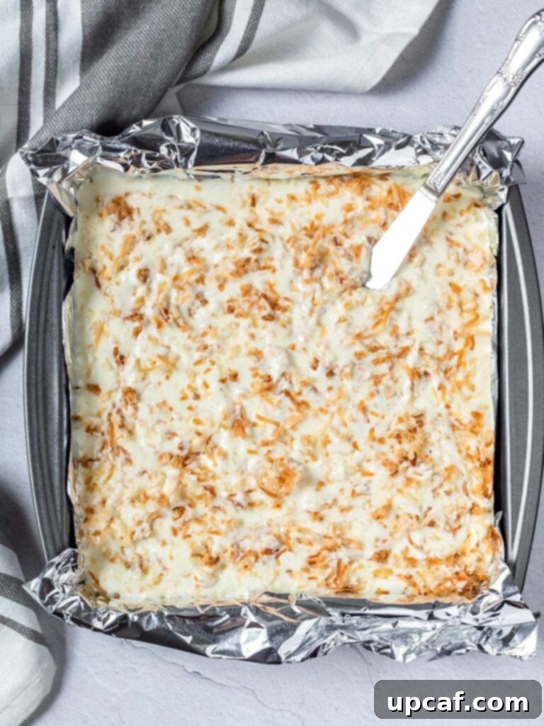 Smooth, creamy coconut cheesecake filling poured into a 9x9 inch pan with a golden graham cracker crust, ready for baking
