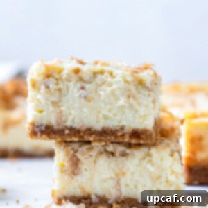two cheesecake bars stacked up on each other, showing the creamy filling and toasted coconut