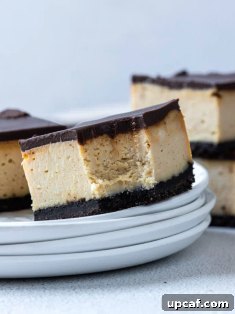 A slice of Chocolate Peanut Butter Cheesecake Bar on a white plate with a bite taken out, showcasing the distinct layers of crust, cheesecake, and ganache.