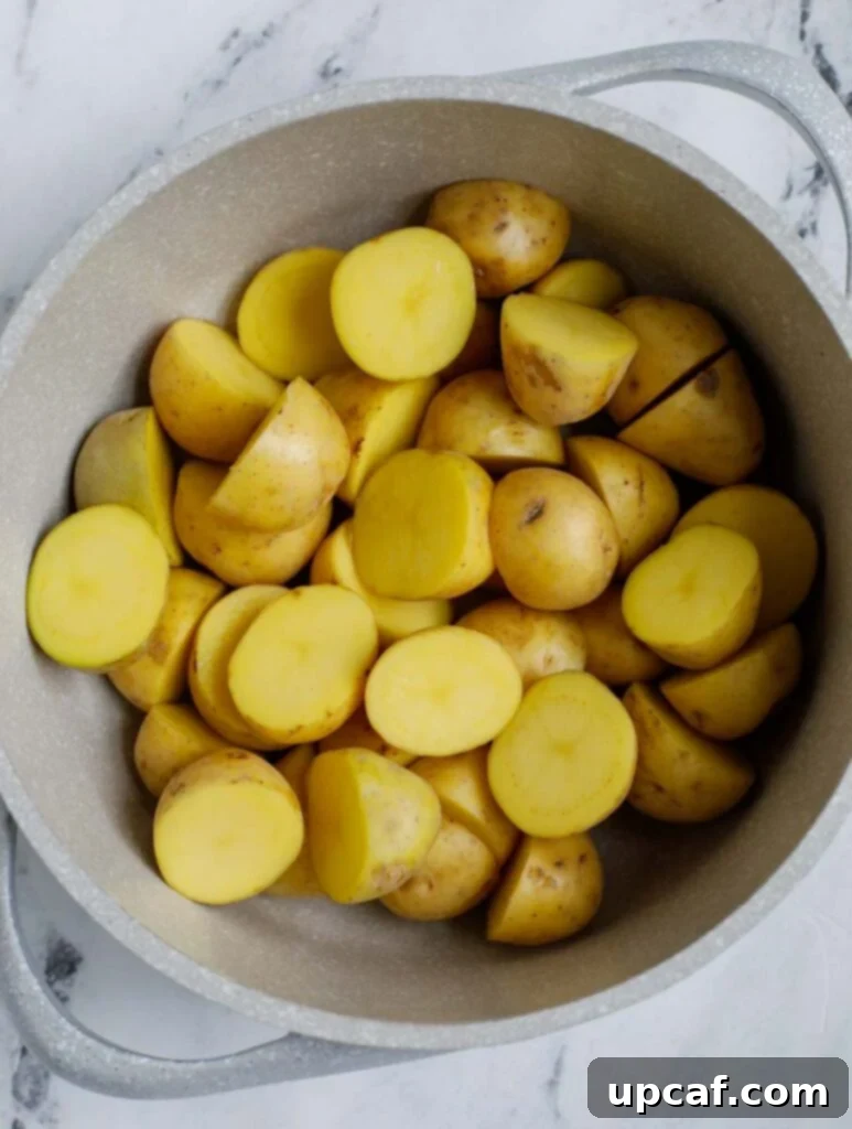 Top down shot of uncooked potatoes in a white bowl, ready for prep.