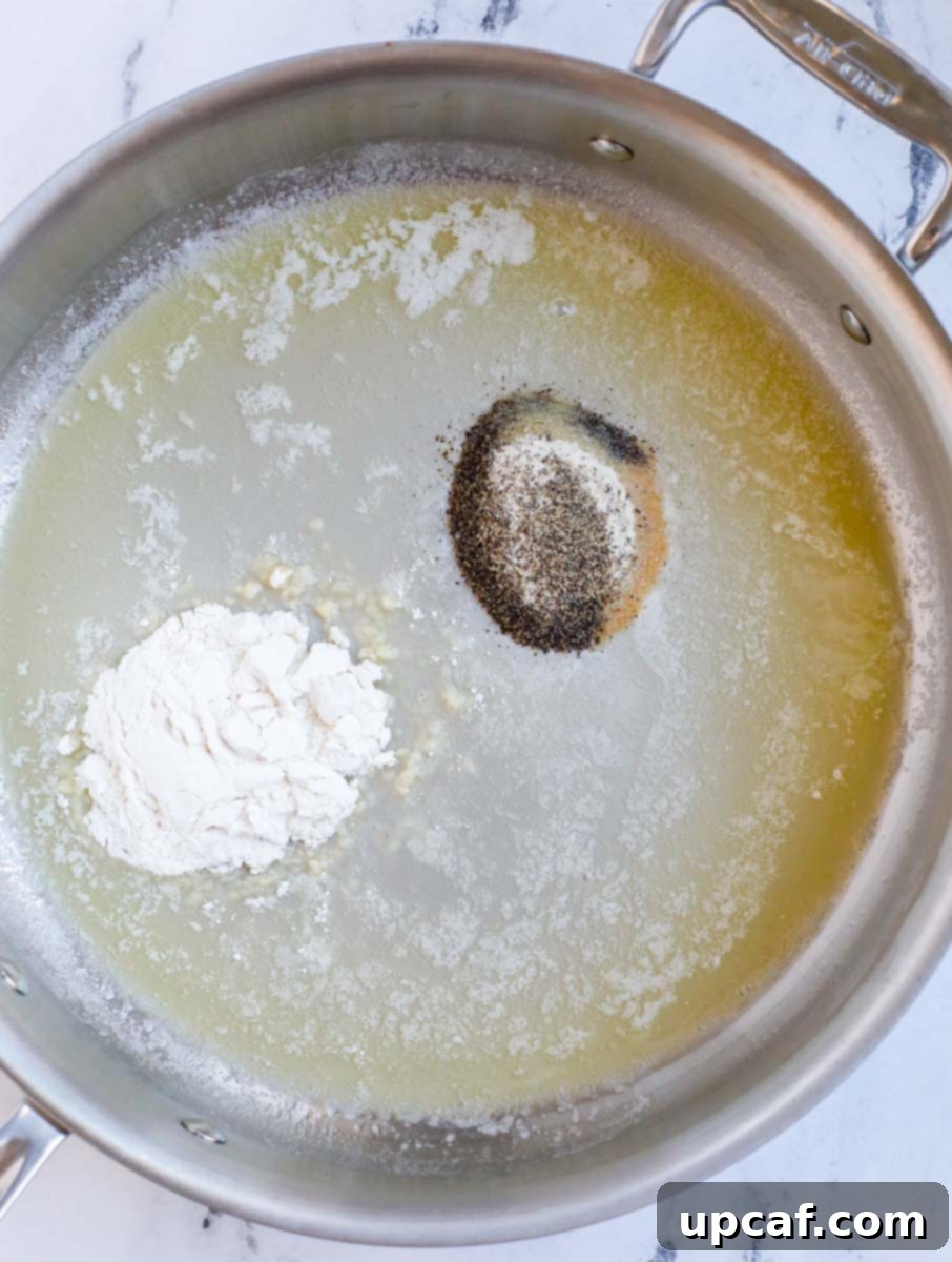Melted butter, oil, spices, and flour cooking in a silver skillet to form a roux.