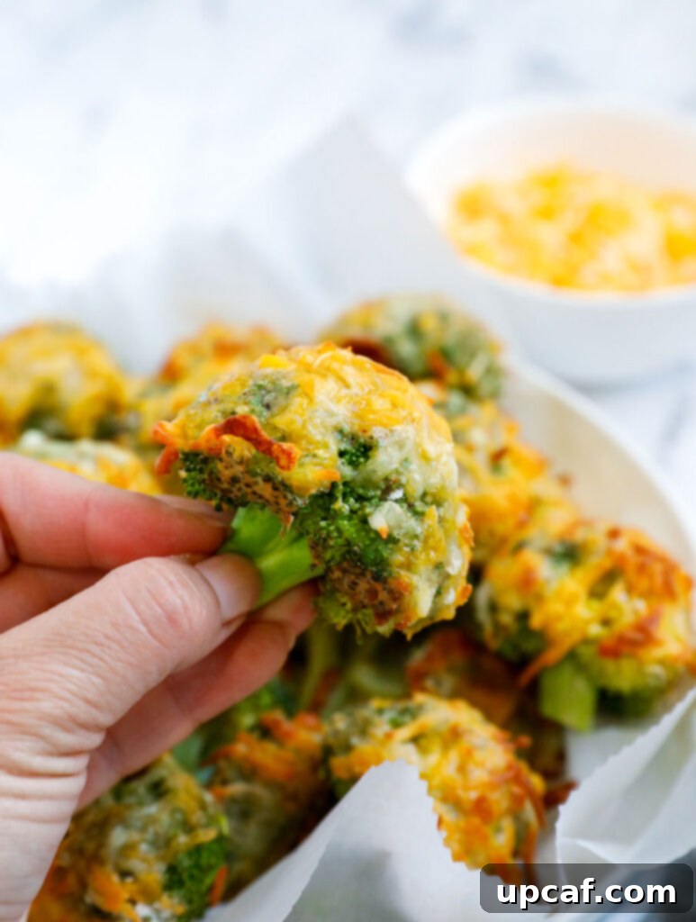Hand holding a cheesy broccoli bite. 