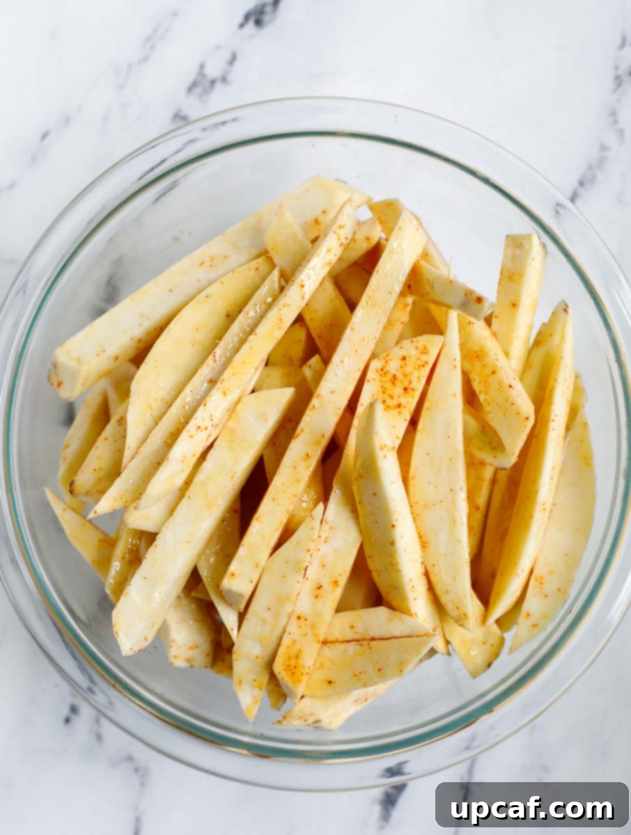 Coating sweet potato slices in a bowl.