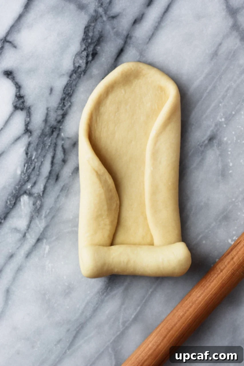 Dough being rolled out and folded, preparing for the loaf pan.