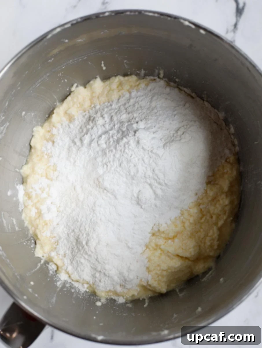 Zesty Holiday Fruitcake 11 The dry flour mixture being slowly added to the wet ingredients in the mixing bowl.