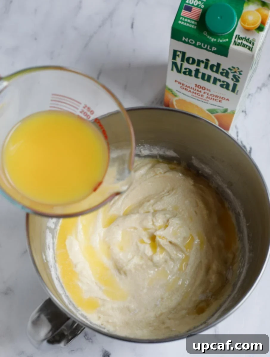 Zesty Holiday Fruitcake 12 Fresh Florida's Natural orange juice being poured into the cake batter, adding essential moisture and flavor.