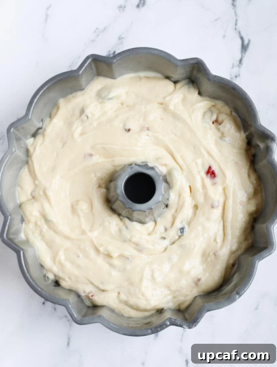 Zesty Holiday Fruitcake 17 The cake batter being carefully poured into the prepared Bundt pan, filling it evenly.