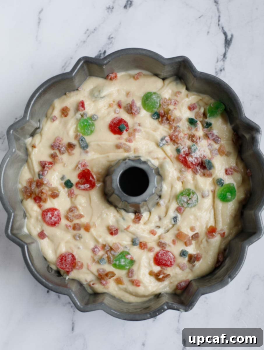 Zesty Holiday Fruitcake 18 The filled Bundt pan with cake batter, adorned with a final scattering of dried fruits on top.