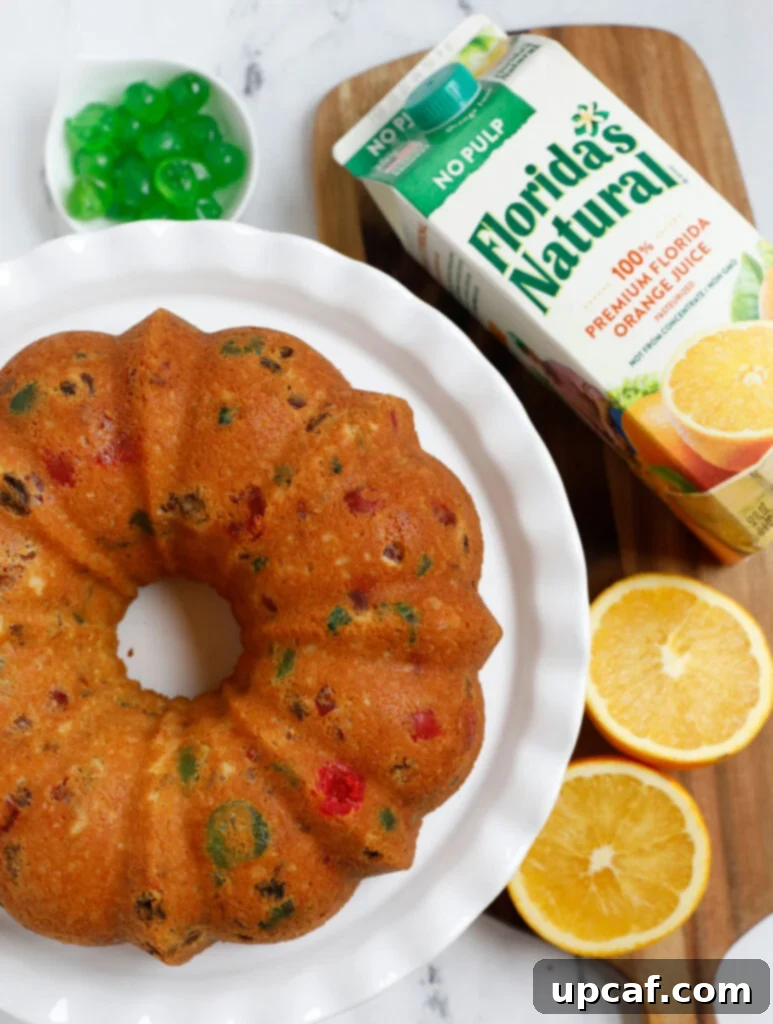 Zesty Holiday Fruitcake 20 A perfect slice of orange fruit cake on a white serving dish, revealing its moist interior and generous distribution of colorful dried fruits.