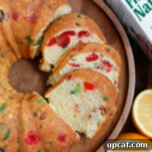 Zesty Holiday Fruitcake 22 Beautifully sliced orange holiday fruit cake served on a wooden plate, ready to be enjoyed.