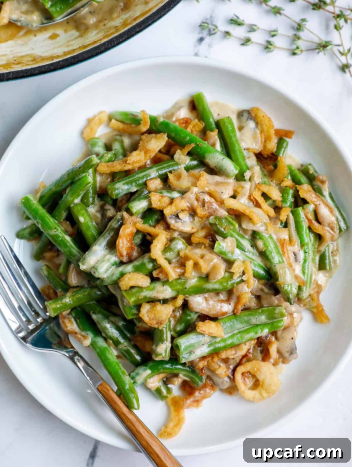 Ultimate Homestyle Green Bean Casserole 10 A white plate featuring a generous serving of homemade green bean casserole, ready to be enjoyed.