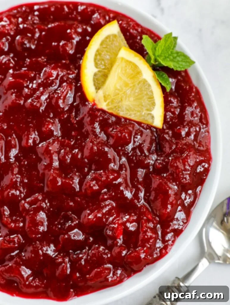 Close up shot of homemade cranberry sauce served in a white dish, garnished with fresh cranberries and orange zest.