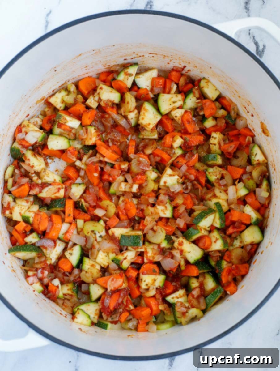 Rustic Vegetable Minestrone 6 Vegetables being sautéed with tomato paste and spices in a large pot.