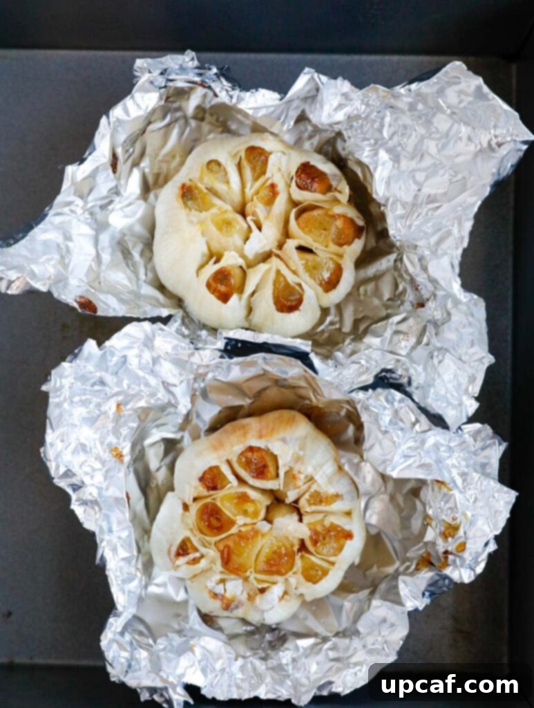 Roasted garlic bulbs wrapped in foil, ready to be unwrapped and used.