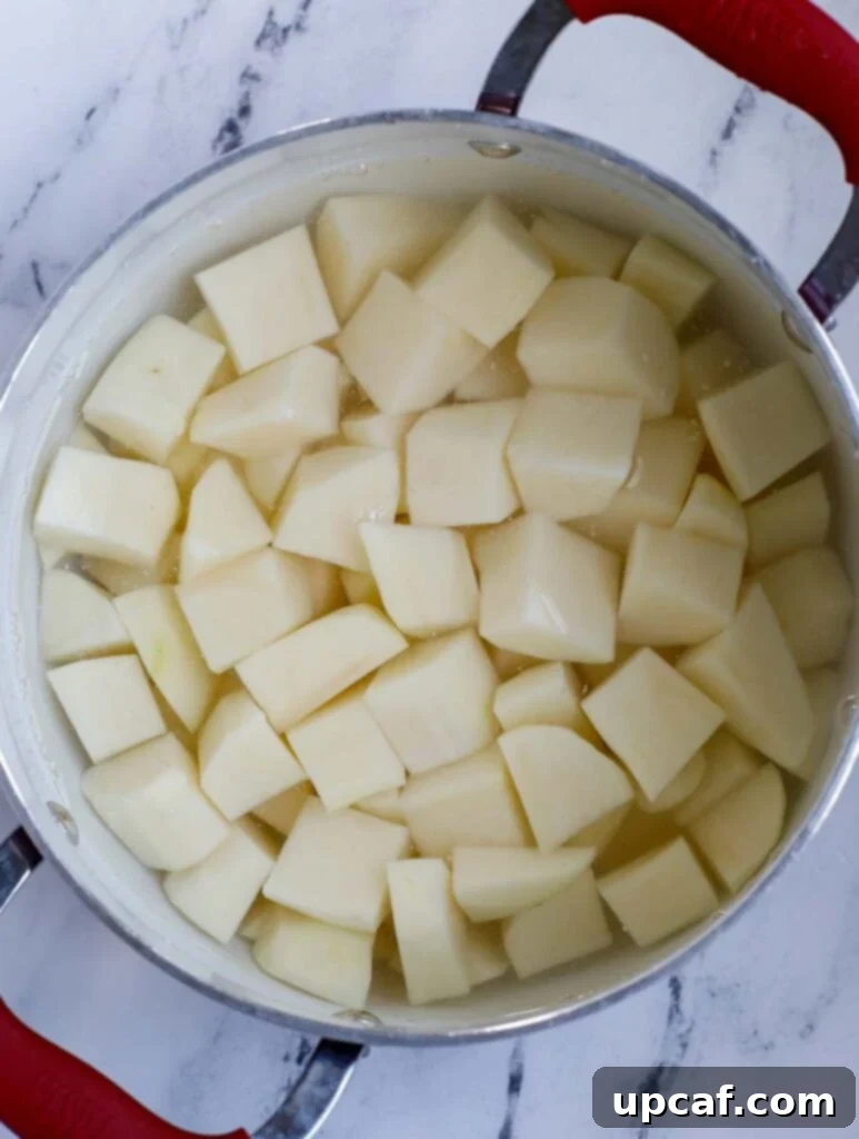 Diced russet potatoes in a large pot, covered with water and ready for boiling.