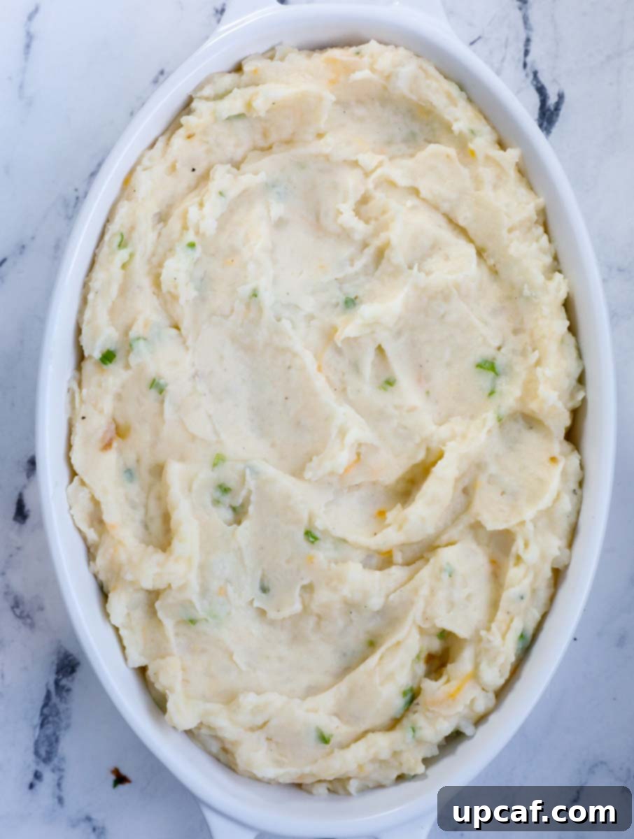 Mashed potatoes smoothed out in a greased baking dish, ready for the oven.