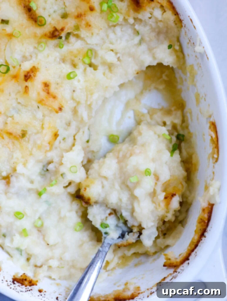 A top-down view of mashed potatoes in a baking dish with a portion scooped out, ready to be served.