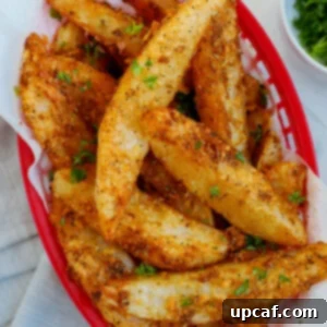 Top down view of crispy potato wedges in a red basket.
