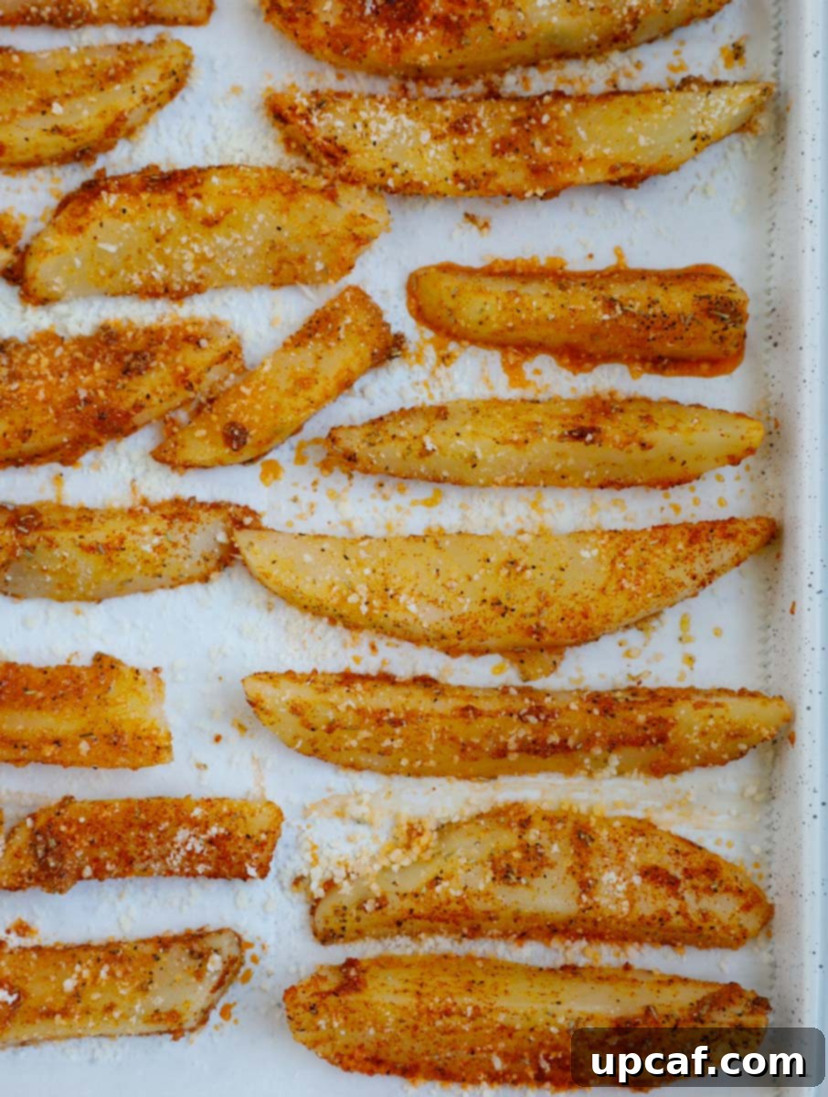 Overhead view of potato wedges on a tray before baking.