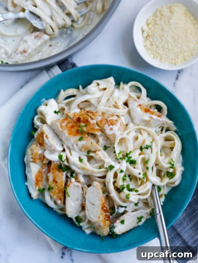 Overhead shot of creamy chicken alfredo pasta on a blue plate, garnished with fresh parsley.