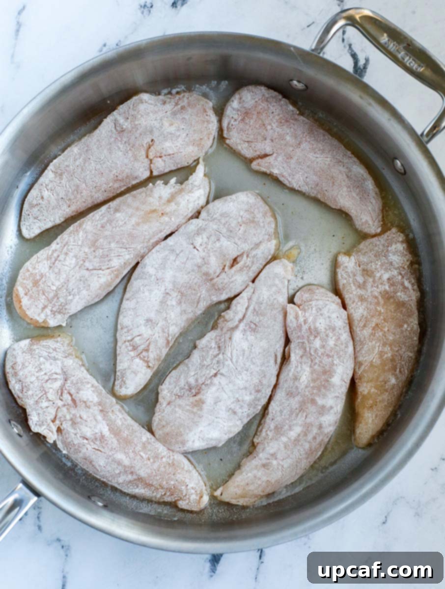 Chicken tenders placed in a hot pan for searing.