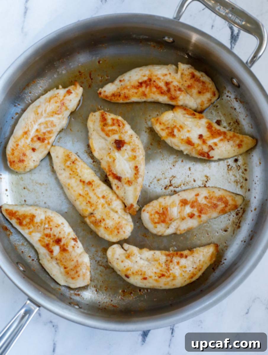 Chicken tenders turning golden brown as they cook in a pan.