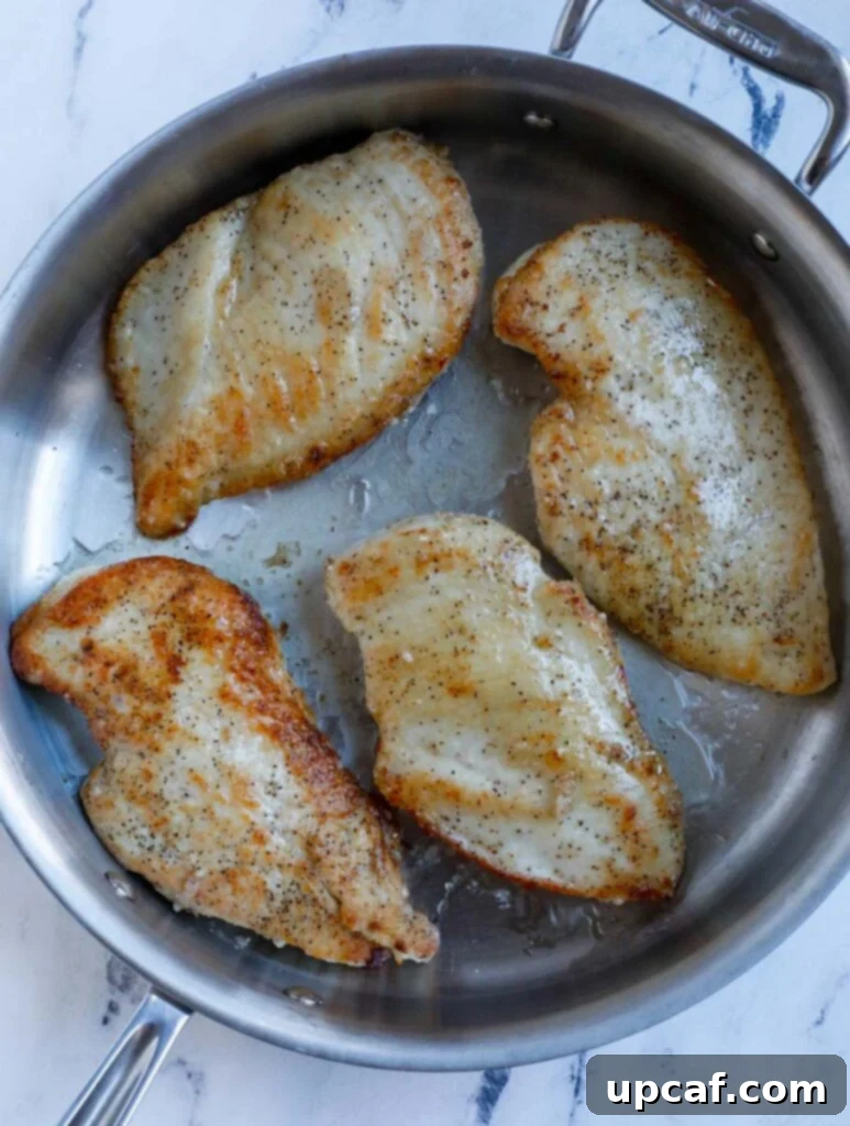 Chicken breasts searing in a hot pan.