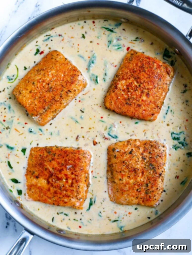 Overhead shot of salmon fillets perfectly nestled in the creamy Tuscan sauce.