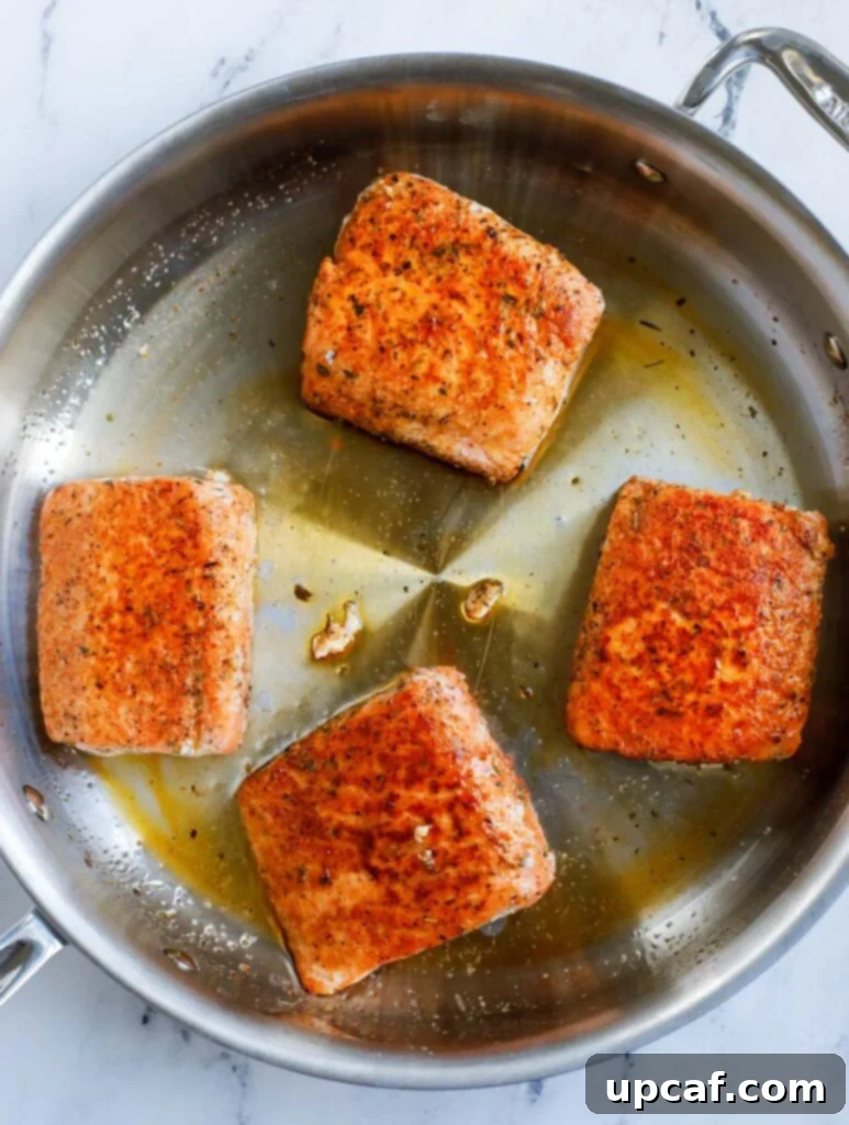 Pan searing the salmon in a pan to achieve a golden crust.