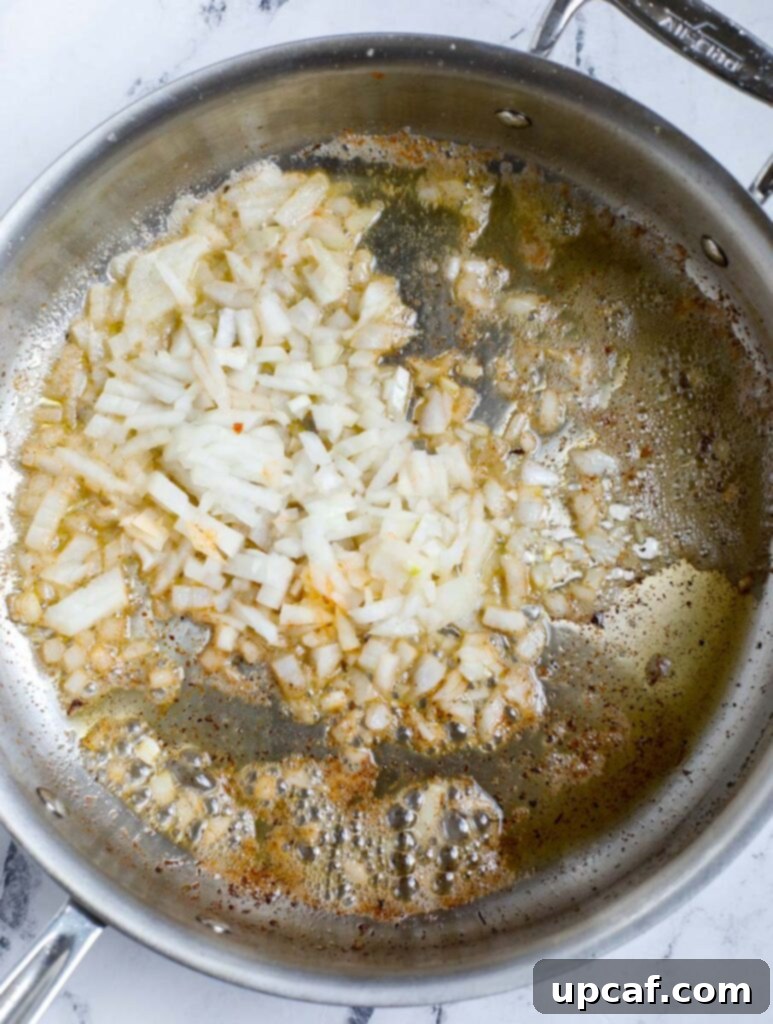 Top down view of sautéed onion in a skillet.