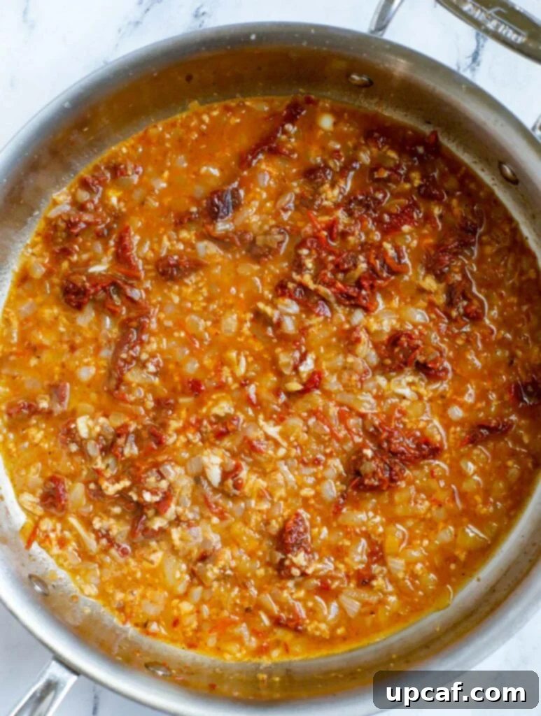 The mixture of garlic, herbs, and broth simmering gently in the pot.