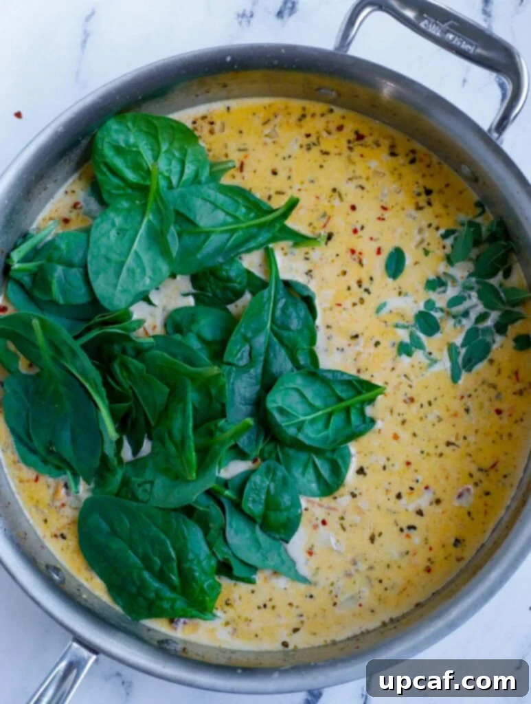 Fresh spinach wilting into the rich cream sauce.