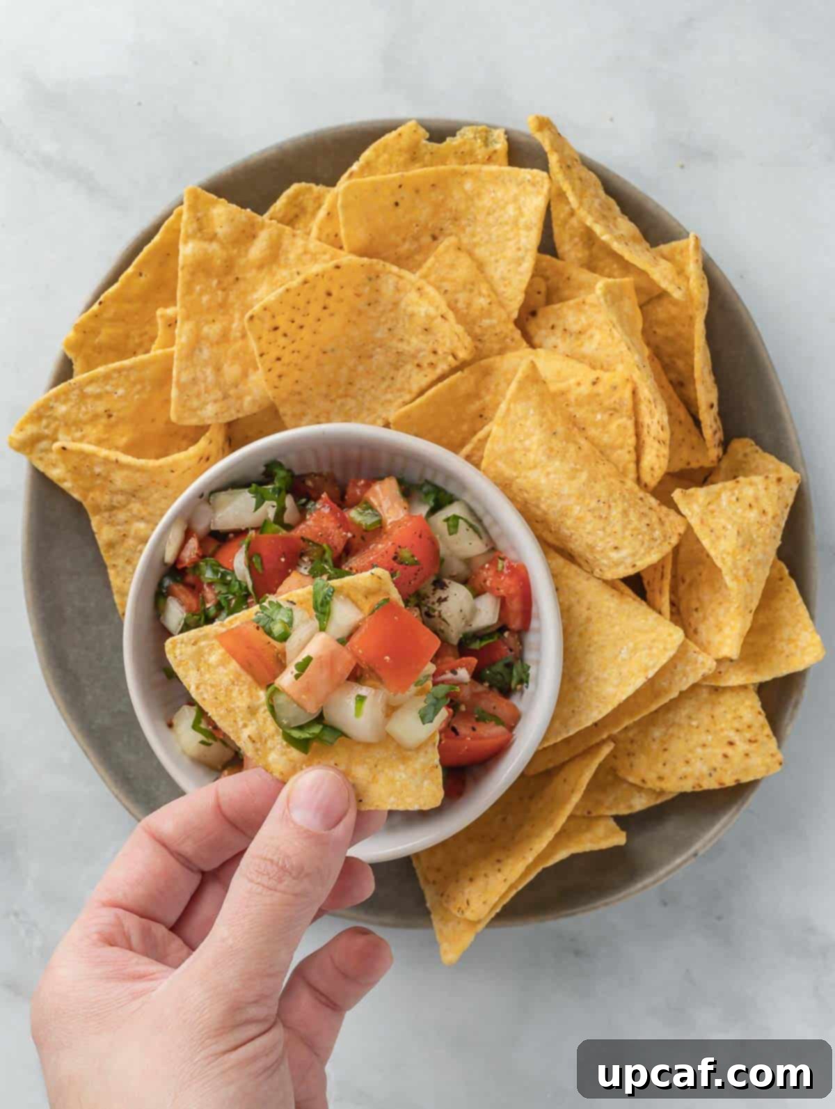 hand scooping pico de gallo.