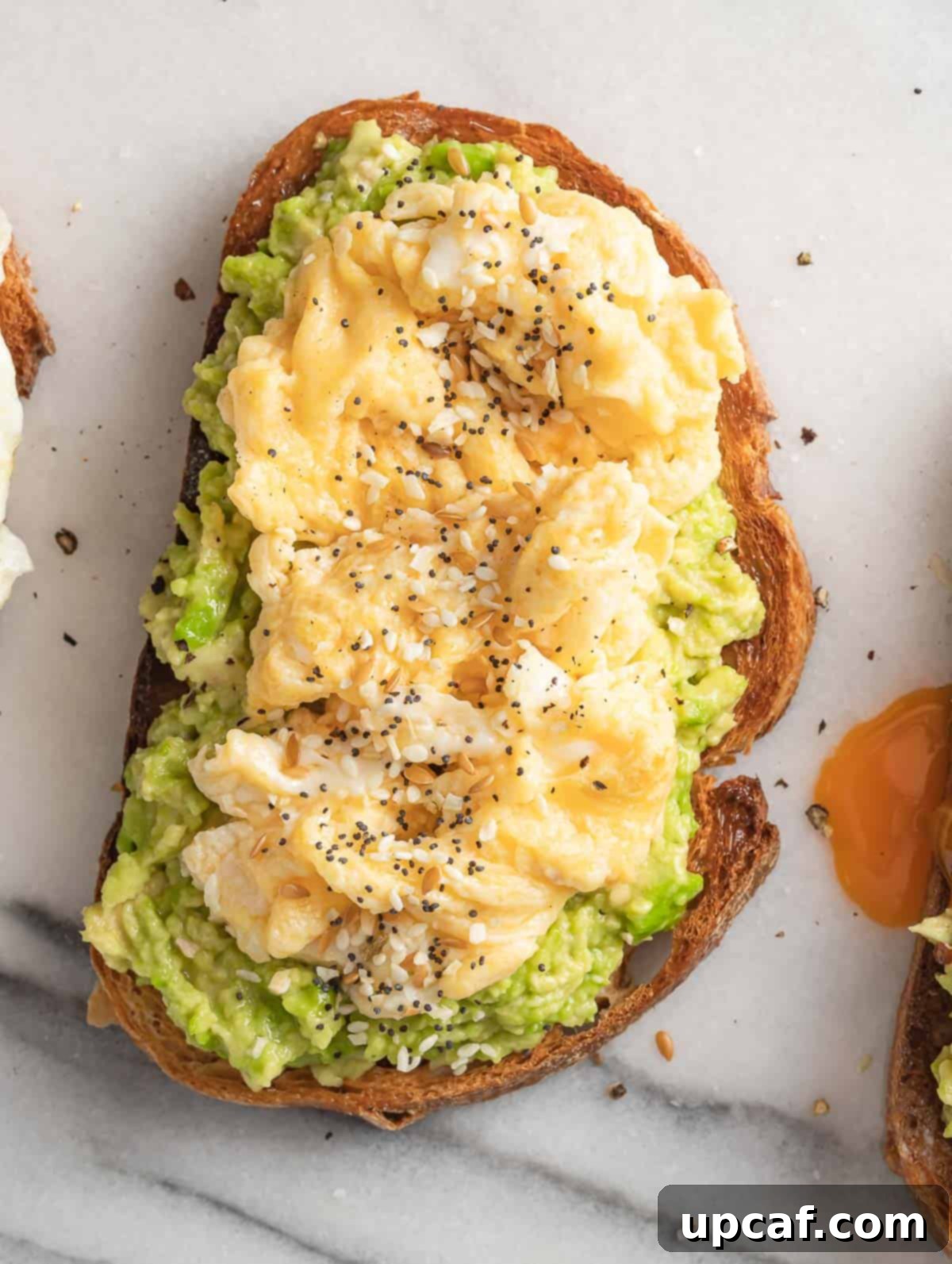 Avocado on toast bread topped with fluffy scrambled egg and a sprinkle of chili flakes.