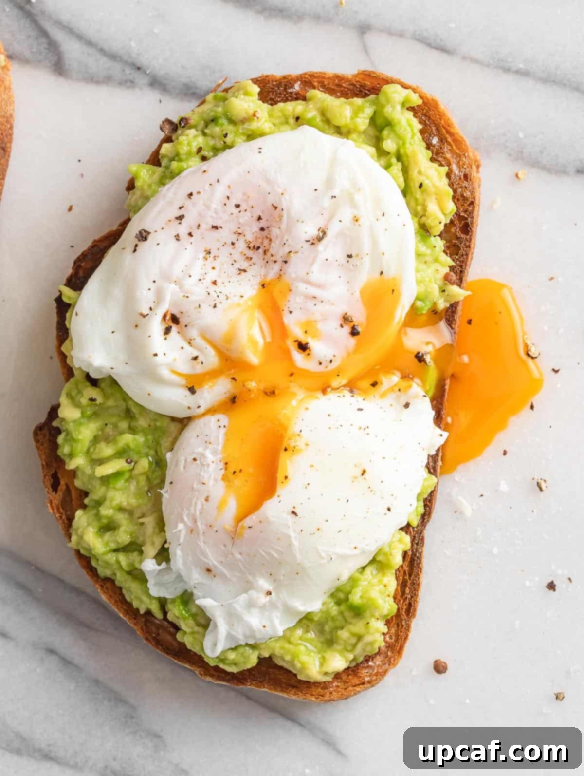 Avocado on toast bread topped with a perfectly poached egg, ready to burst.