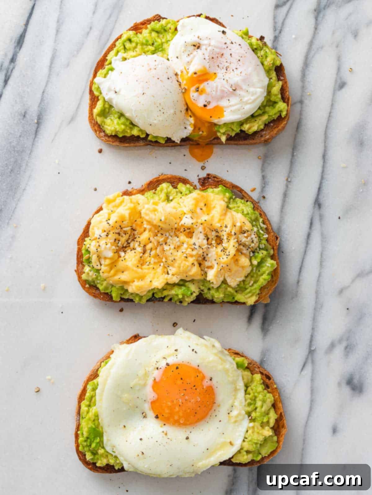 Three perfectly styled avocado toasts, each topped with a different egg style: fried, scrambled, and poached.