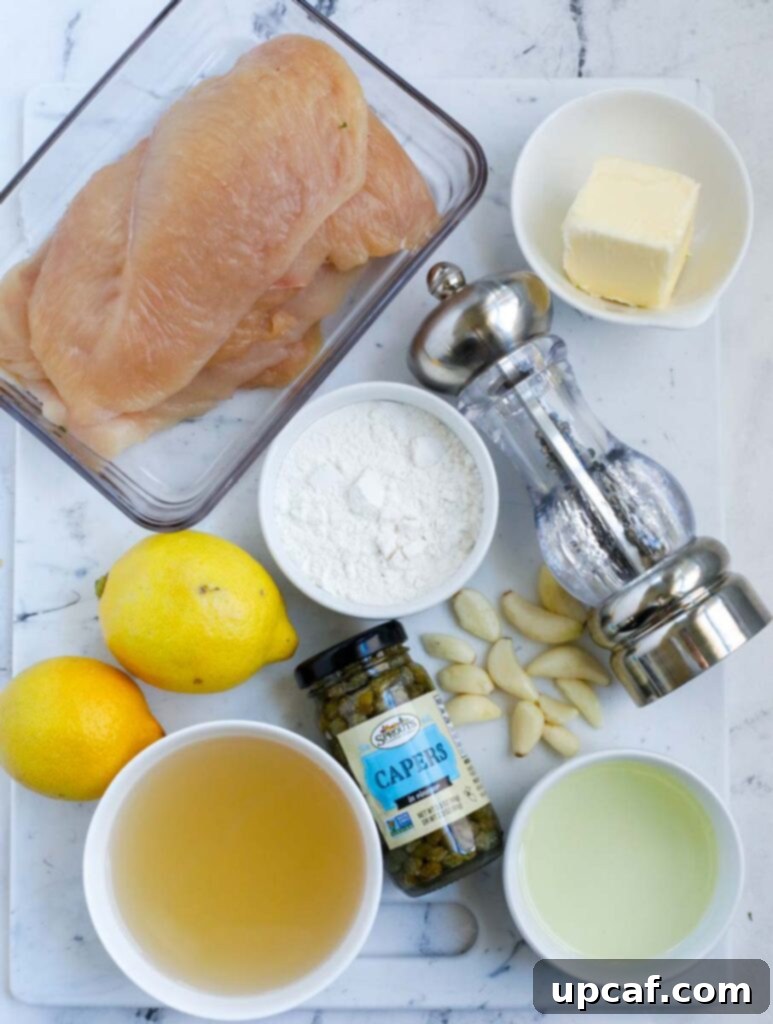 A collection of fresh ingredients laid out for lemon chicken piccata preparation, including chicken breasts, lemons, capers, garlic, butter, and olive oil.