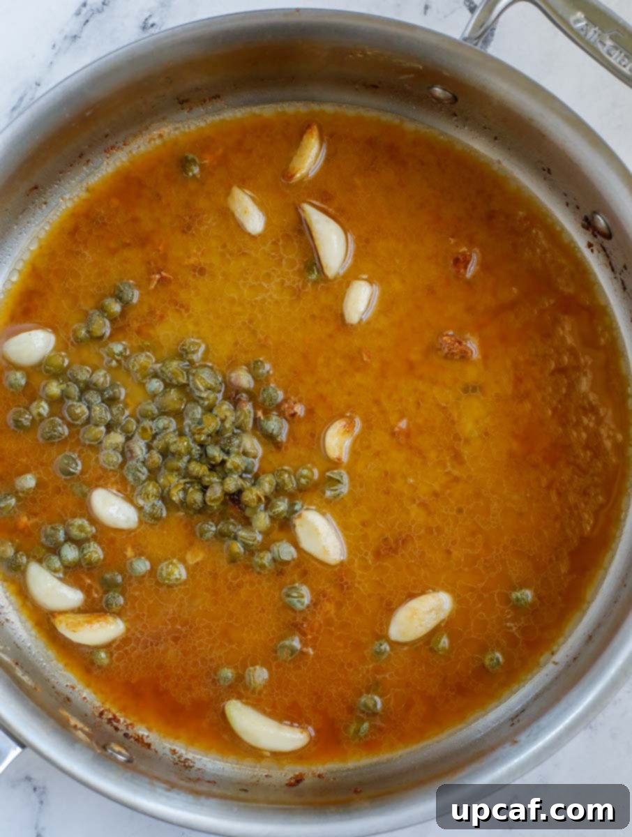 Close-up of the lemon caper sauce simmering in a pan, releasing its rich aromas.